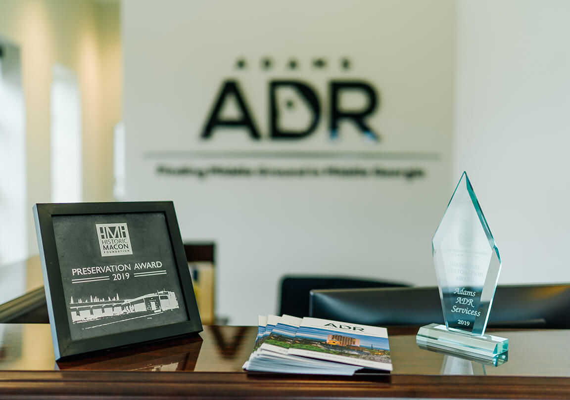 front desk with Adams ADR logo behind, and awards on the counter top