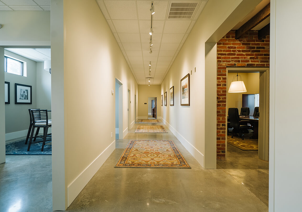 a long hallway with polished concrete floors and rugs
