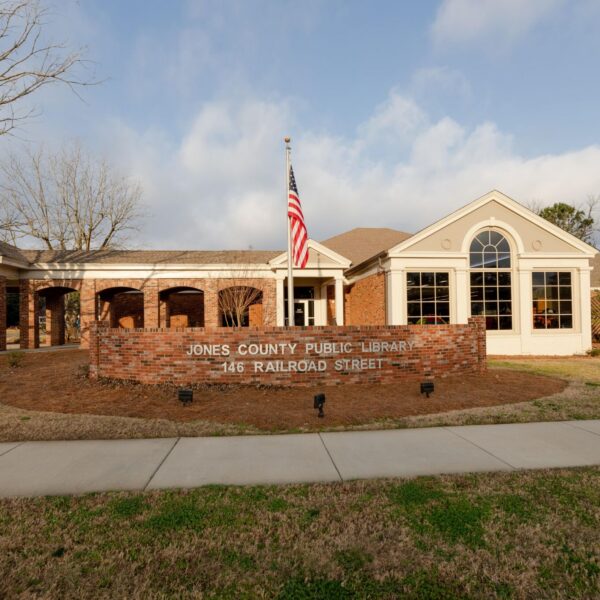 The Jones County Public Library at 146 Railroad Street with brick exterior, large arched windows, leafless trees, and an American flag.