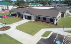 Aerial view of a modern, single-story building labeled Douglas City Hall with landscaped lawn, two flagpoles, parking, and roads.
