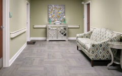 Hallway with light green walls, gray carpet, wood doors, a patterned sofa, side table, and a console under an abstract painting.