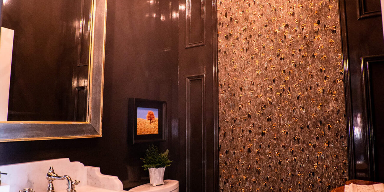 Luxurious bathroom with dark glossy walls, white toilet and sink, chandelier, decorative mirror, marble countertop, textured panel.