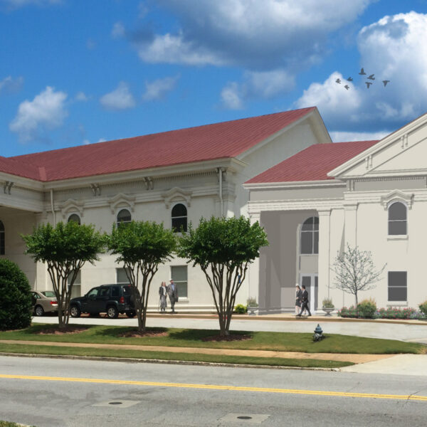A large, light building with columns and a red roof sits under a blue sky. People walk by; trees, bushes, and birds add life above.
